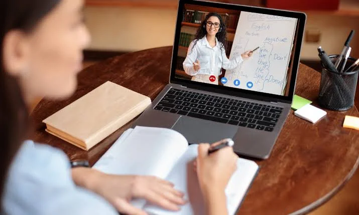 Une personne suit une leçon en visioconférence avec une enseignante.